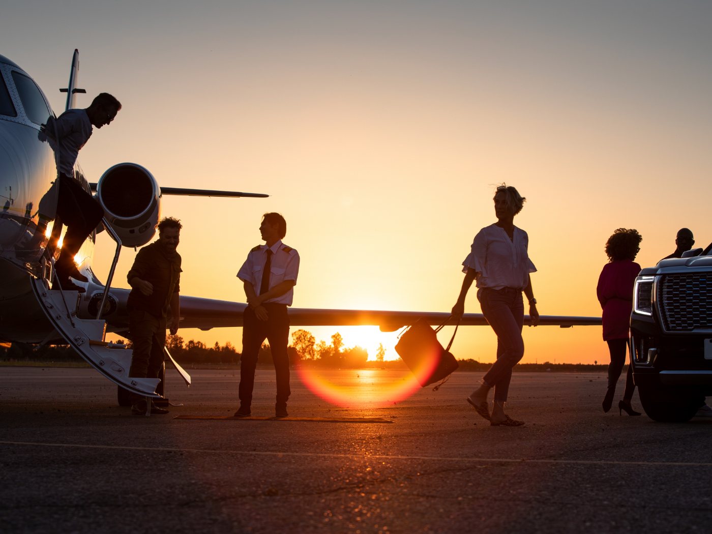 Passengers and crew beside a business jet at sunset