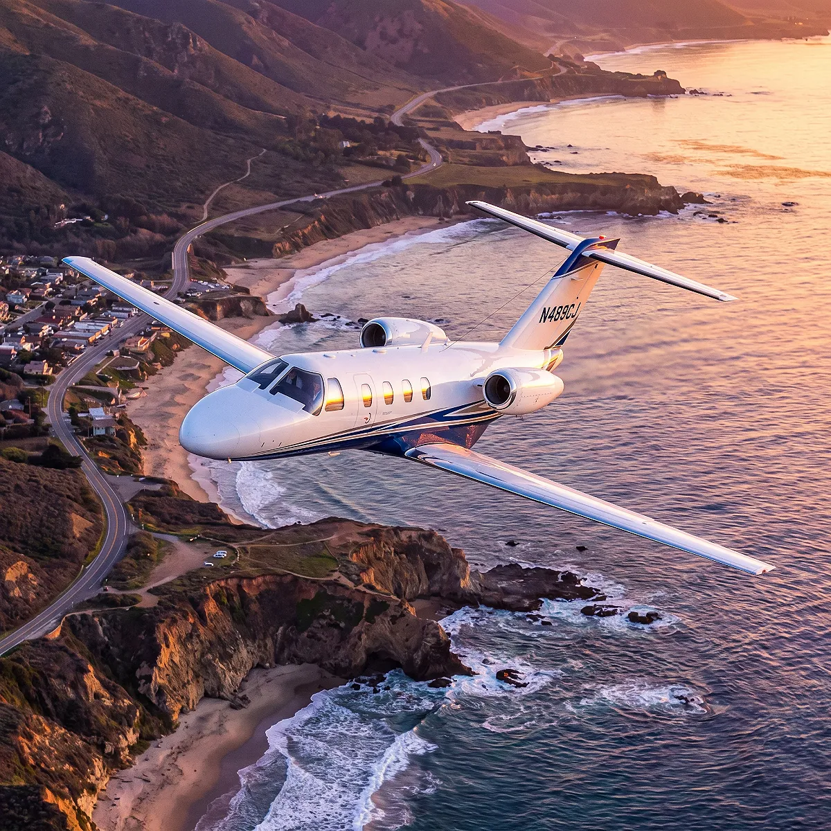 Light jet in flight above a coastline at sunset